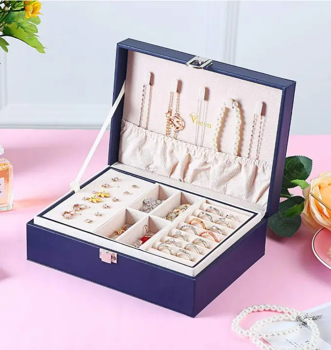 An open navy two-layer Voova jewellery box with necklaces, rings and earrings arranged inside